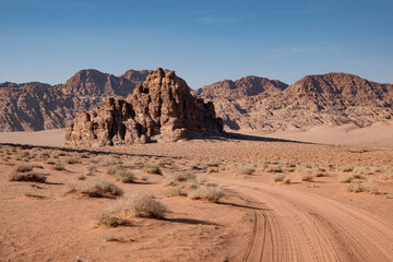 Fototapeta na wymiar A dusty dirt road stretches through the arid landscape of the Wadi Rum desert in Jordan.