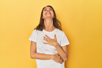Fototapeta premium Middle-aged caucasian woman on yellow laughs out loudly keeping hand on chest.