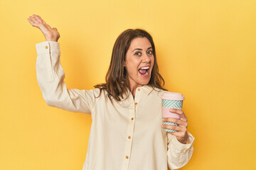 Woman sipping takeaway coffee on yellow background