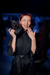 a photographer girl with a camera with a surprised face and a smile on a blue background
