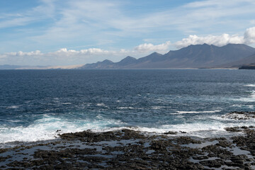 View on difficult to access golden sandy long Cofete beach hidden behind mountain range on Fuerteventura, Canary islands, Spain