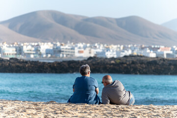 West coast of Fuerteventura island. Winter sea and sun vacation in El Cotillo touristic village, Canary islands, Spain. Unidenfitied old couple relaxing on white sandy beach La Concha..