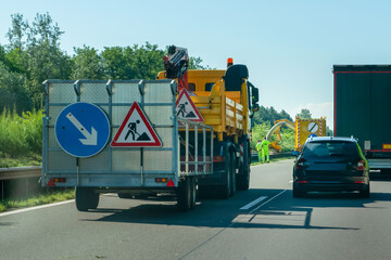 Triangular red traffic sign on back of truck indicating that there is work on the road and...