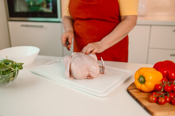 Obraz na płótnie Canvas Housewife cutting chicken meat enjoy weekend morning cooking tasty dinner family husband children stand bright light kitchen indoors. High quality photo