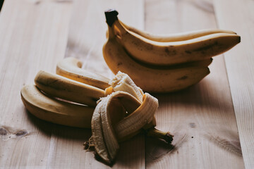 Close-up of peeled sliced banana on wooden table background - obrazy, fototapety, plakaty