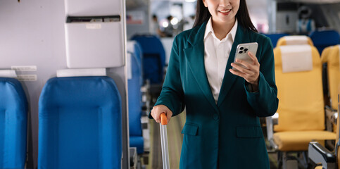 Fototapeta na wymiar Attractive Asian female passenger of airplane sitting in comfortable seat while working laptop and tablet with mock up area using wireless connection.