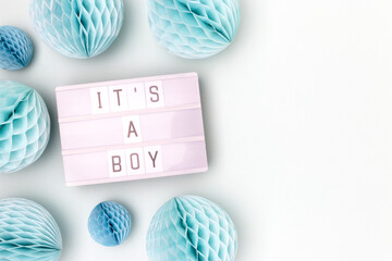 It's a boy. Lightbox with letters and tissue paper balls in a blue color. Baby shower concept with place for your design.