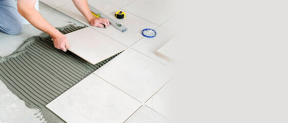 A man lays tiles on the floor, a place for text