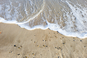 Des bulles de l'ecume des vagues sur un sable blond d'une plage paradisiaque de vacances