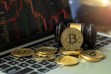 Cryptocurrency laws. bitcoins and gavel on a laptop with Golden Scale for Cryptocurrency...