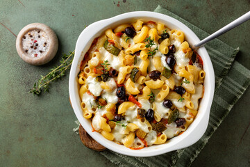 Top view of oven baked pasta macaroni with vegetables, olives, zucchini, carrots and mozzarella cheese with thyme.