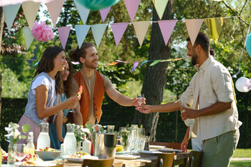 Friends and family talking and eating barbeque specialties at a summer grill garden party.