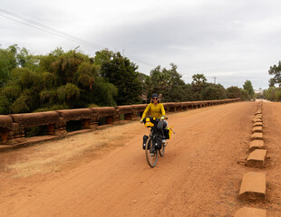 Traveler nomadic woman on her bicycle loaded with bags passing 