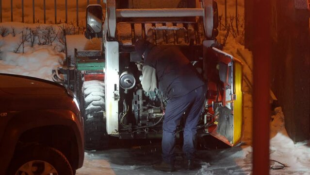 Man repairing utility work machine for snow removal in winter. Bobcat with snow removal attachment