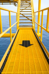 Steel netting creates walkways on oil and gas drilling platforms, painted white and yellow and with arrows to guide the walkways.