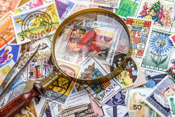 Ukraine, Kiyiv - January 12, 2023.Postage stamps.Collection of stamps and magnifying glass.A collection of world stamps in a pile.Postage stamps from different countries and times - obrazy, fototapety, plakaty