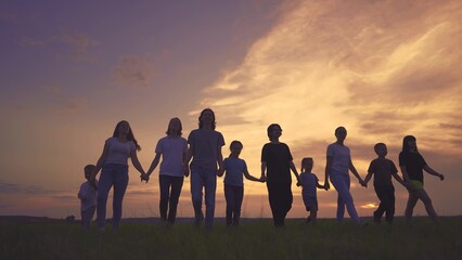large friendly community family silhouette walk in the park. friendly family holding hands walking...