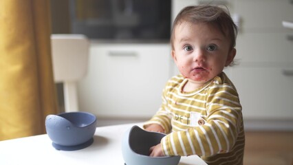 grimy baby eats with her hands from a plate. development of fine motor skills family kid dream concept. funny video baby dirty eats food from a plate with his hands. dirty baby eats lifestyle