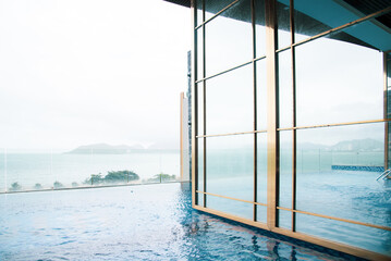 Glass wall of Infinity pool with ocean and mountain range view at luxury resort hotel in Nha Trang, Vietnam, upscale healthy lifestyle, Asia travel destination, relaxation and recreation - obrazy, fototapety, plakaty