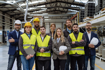 Full team of warehouse employees standing in warehouse. Team of workers, managers, female director and worker with down syndrome in modern industrial factory, heavy industry, manufactrury. - obrazy, fototapety, plakaty