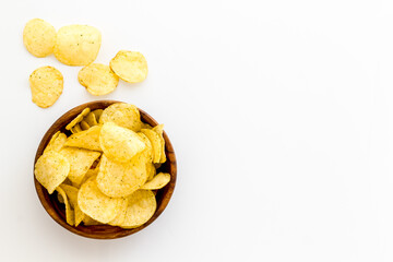 Wooden bowl of crispy potato chips, top view. Fast food and snack background