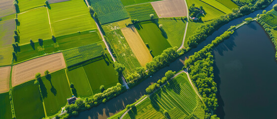 Fototapeta premium Banner of aerial satellite view of cultivated agricultural farming land fields as a typical European or countryside farmland village town with canal river
