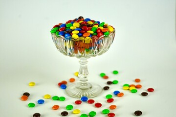 round multi-colored candies in a beautiful vase on a white background