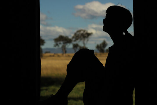 Silhouette of a young girl sitting in a window frame