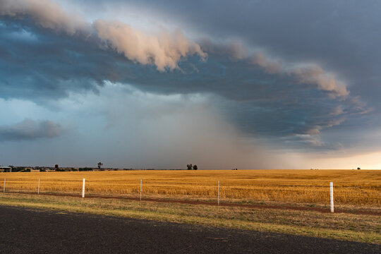 Rain falling from a dramatic stormfront over rural farmland