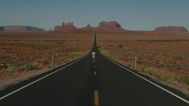 Cinematic shot of man running up to camera on incredible majestic desert highway road in epic Monuments Valley Arizona.