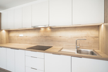 A Modern kitchen with white cabinets, a wooden countertop, a built-in sink, an induction cooktop,...