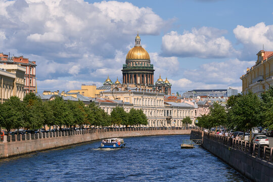 View of St. Isaac's Cathedral and pleasure boat with tourists form Moika river in Saint-Petersburg (Russia)