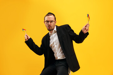Portrait of man in his 30s wearing glasses, yarmulke and playing with noisemaker, gragger,...