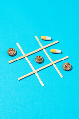 Tic tac toe game with medical pills on blue background