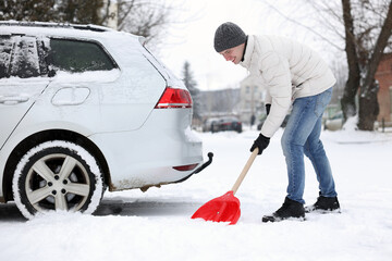 Man removing snow with shovel near car outdoors © New Africa