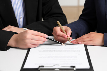 Businesswoman showing client where to sign document at white table, closeup