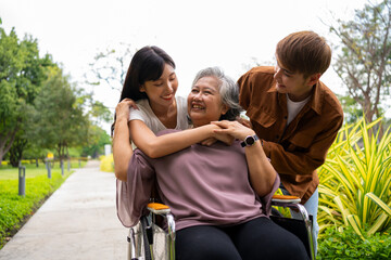 Asian careful caregiver or nurse taking care of the patient in a wheelchair.  Concept of a happy retirement with care from a caregiver and Savings and senior health insurance, a Happy Family
