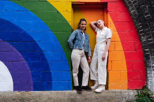 Confident non binary person standing with friend in front of door