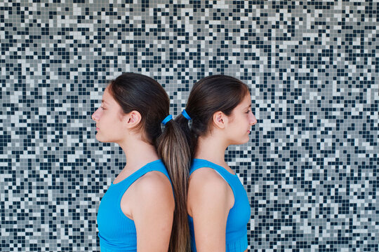 Sisters standing together in front of textured wall
