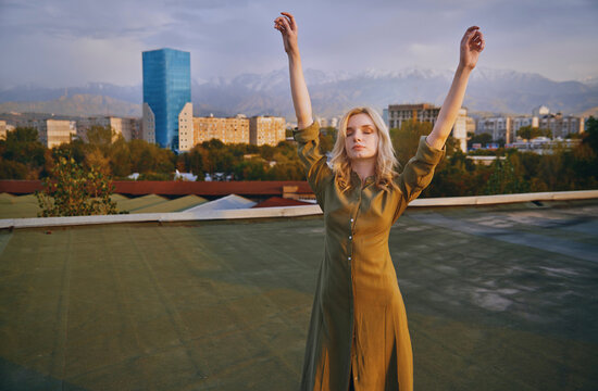 Carefree young woman with arms raised dancing on rooftop