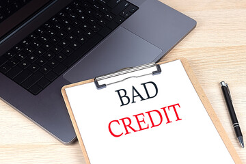 BAD CREDIT text written on a paper clipboard on laptop