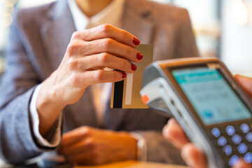 Close-up Hand of a woman holding a credit card and making a payment transaction.
