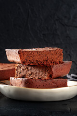 Chocolate brownie, simple coffee cake, a side view on a black background with copyspace, a close-up