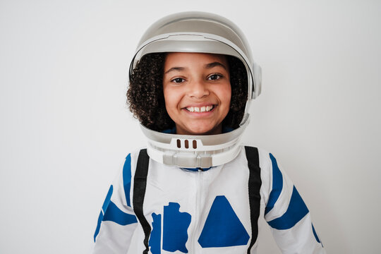 Happy girl wearing astronaut's costume in front of white wall
