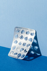 Empty medicine blister pack leaning on blue background.