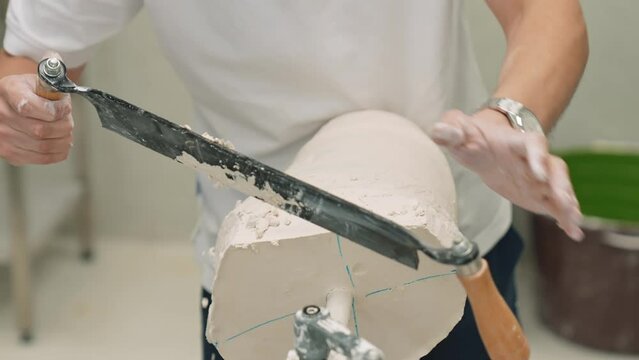 The master of prosthetics prepares a plaster mold for a prosthetic leg. The craftsman files a plaster mold for a leg prosthesis. Manufacture of robotic prostheses, in the center of prosthetics and