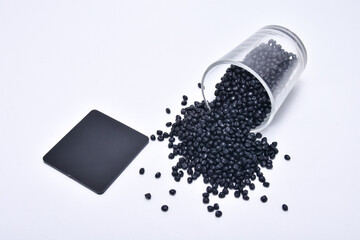 black masterbatch granules spilled from a shot glass, equipped with a color chip as an example of...