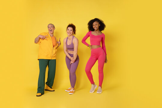Happy multiracial friends standing against yellow background