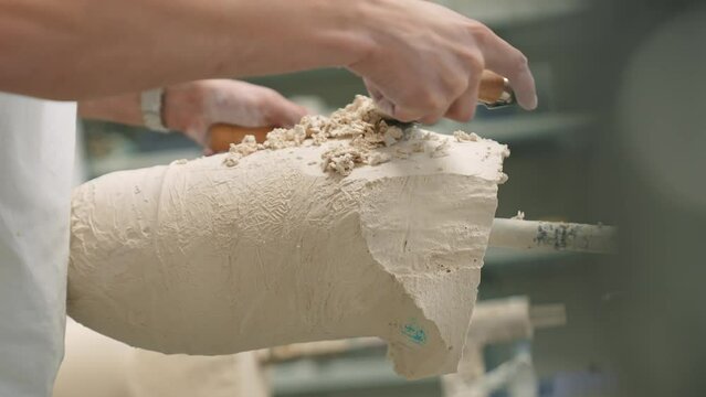 The master of prosthetics prepares a plaster mold for a prosthetic leg. The craftsman files a plaster mold for a leg prosthesis. Manufacture of robotic prostheses, in the center of prosthetics and