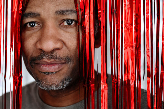Man looking through red tinsel curtain